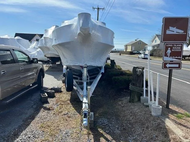 Slide: The Image of 2024 Parker 2520 XLD Sport Cabin boat covered, parked near Long Island Sound Access sign. - 12