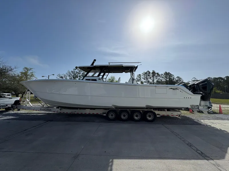Slide: The Image of 2025 Invincible 46 Catamaran on trailer under bright sun, side view. - 1