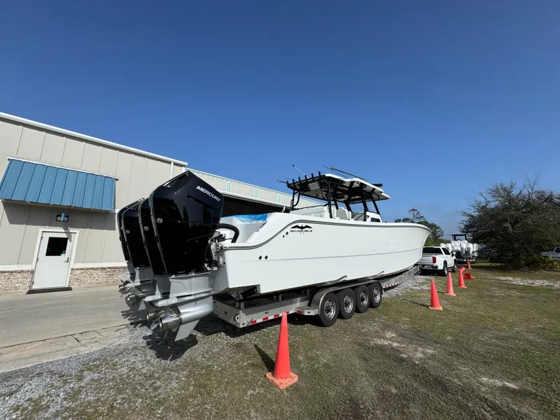 Slide: The Image of 2025 Invincible 46 Catamaran on trailer, parked near building with orange cones. - 14