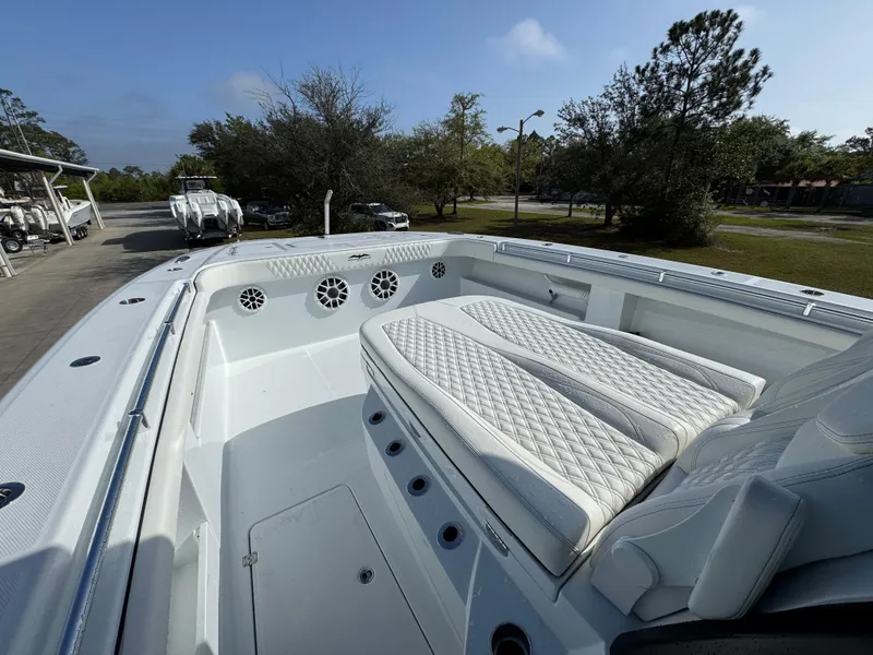 Slide: The Image of 2025 Invincible 46 Catamaran with white seating and speakers, docked outdoors. - 21