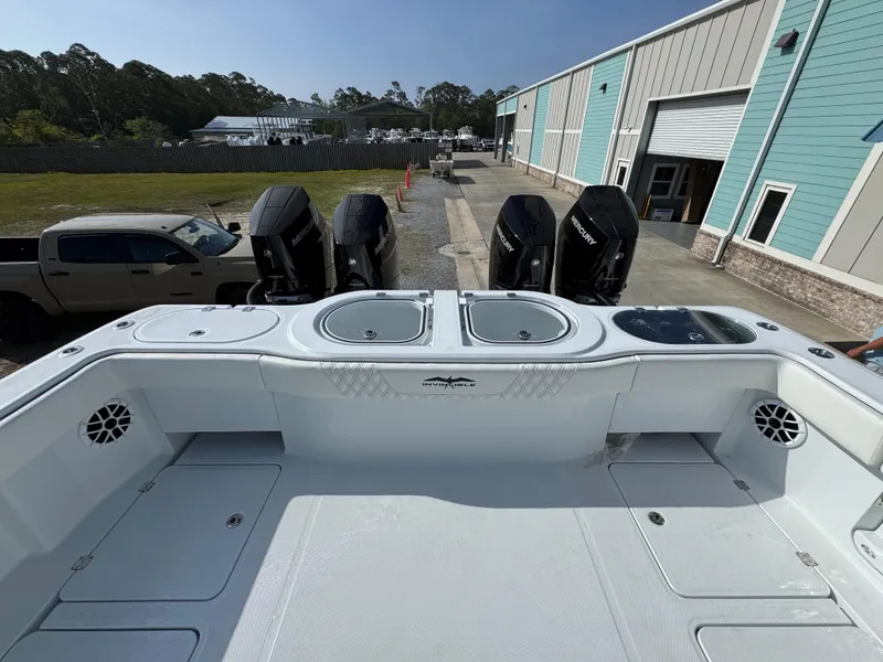 Slide: The Image of 2025 Invincible 46 Catamaran with powerful outboard engines, docked near industrial buildings. - 33