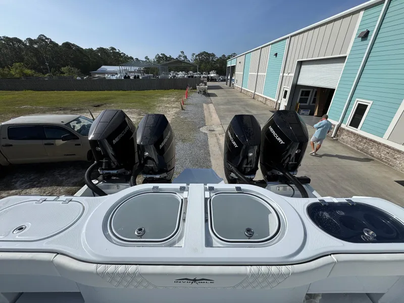 Slide: The Image of 2025 Invincible 46 Catamaran with four powerful outboard motors, docked near a warehouse. - 34