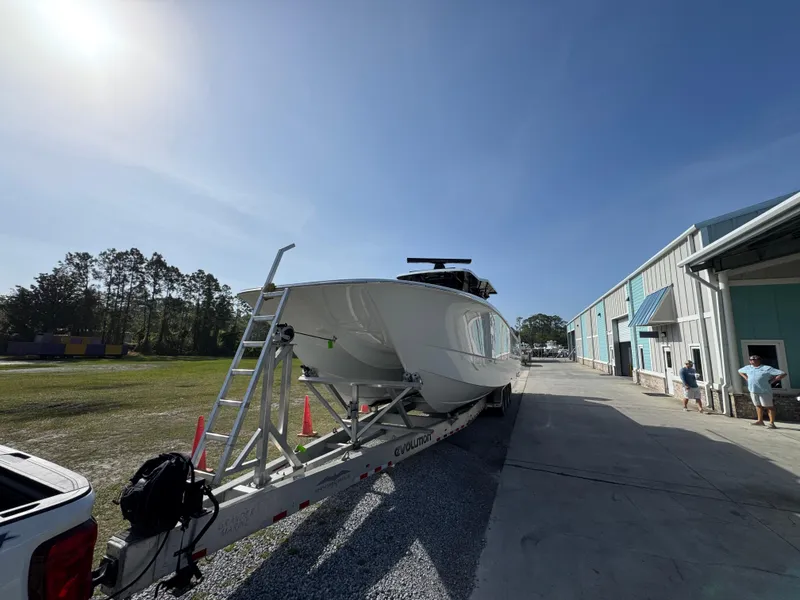 Slide: The Image of 2025 Invincible 46 Catamaran on trailer outside a warehouse under clear blue sky. - 6