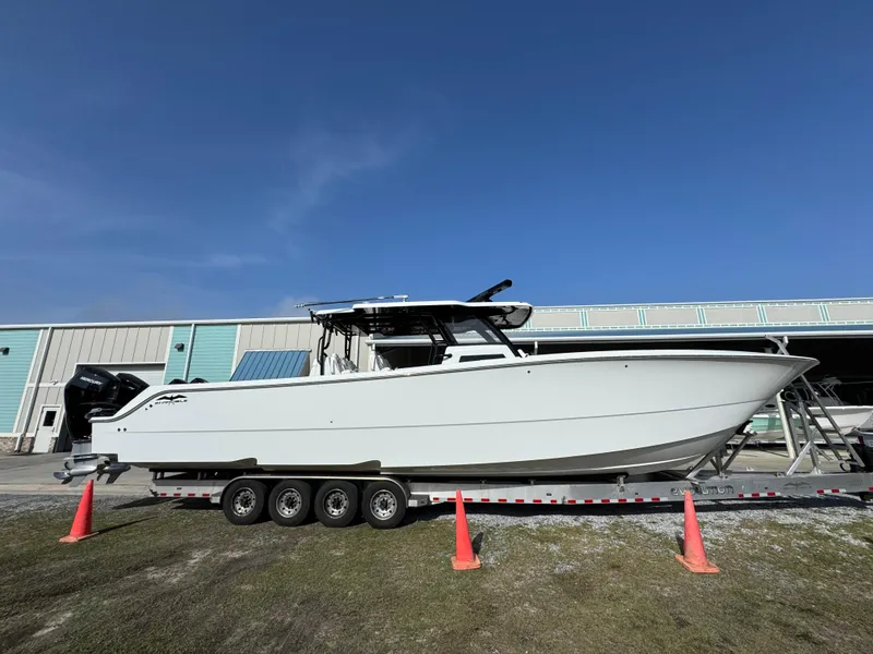 Slide: The Image of 2025 Invincible 46 Catamaran on trailer, parked outside a warehouse under clear blue sky. - 9