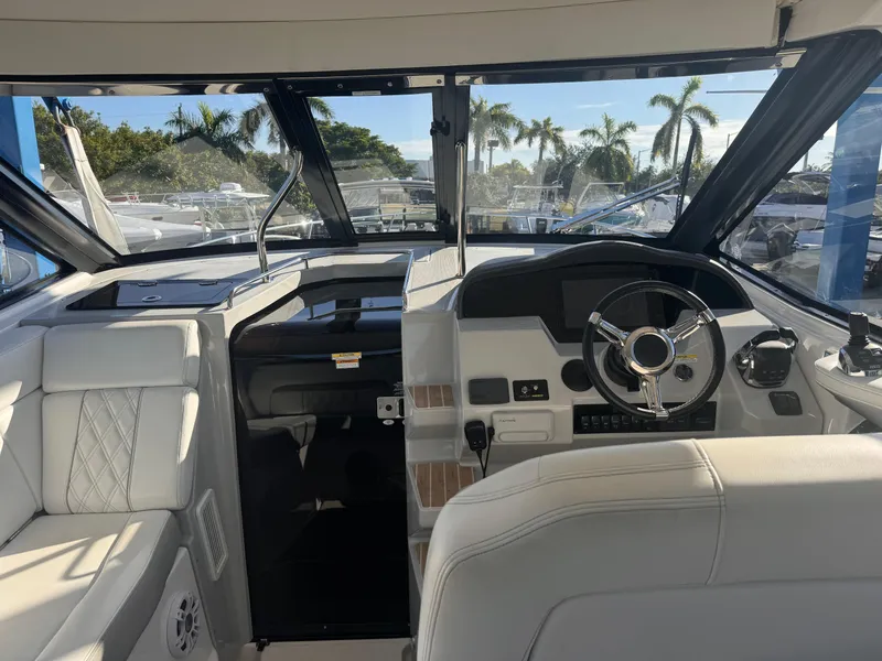 Slide: The Image of 2019 Regal 35 Sport Coupe cockpit with modern steering and dashboard, surrounded by palm trees. - 21