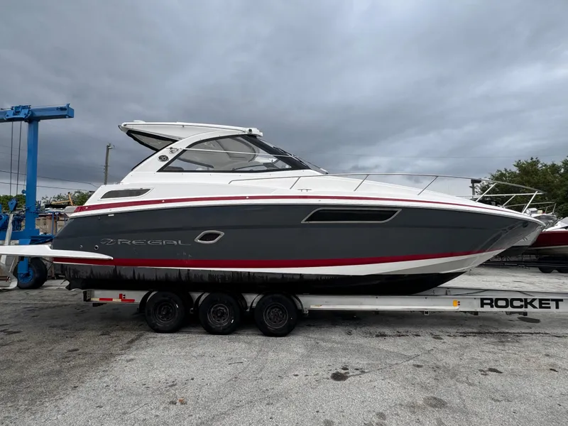 Slide: The Image of 2019 Regal 35 Sport Coupe boat on trailer, gray and white design, overcast sky. - 5
