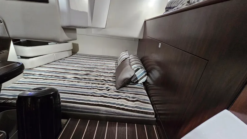 Slide: The Image of Interior cabin of 2020 Monterey 295 Sport Yacht with striped bedding and dark wood accents. - 29