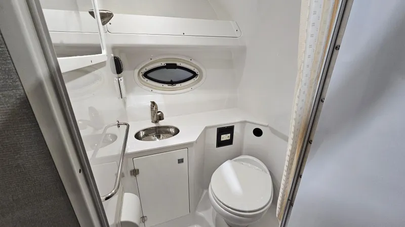 Slide: The Image of 2020 Monterey 295 Sport Yacht bathroom with sink, toilet, and porthole window. - 32