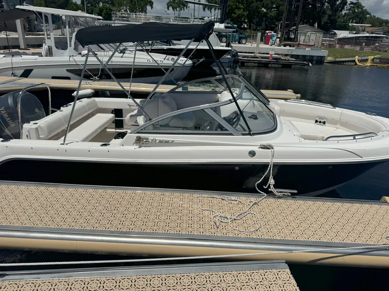 Slide: The Image of 2009 Robalo R227 Dual Console boat docked at marina, featuring sleek design and canopy. - 4