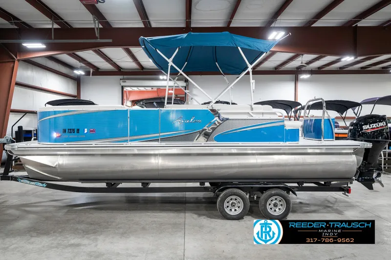 Slide: The Image of 2025 Avalon 2285 LSZ CRB pontoon boat with blue canopy on trailer in showroom. - 11