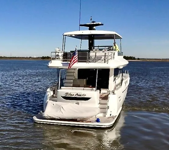 Slide: The Image of 2024 Sirena 68 yacht on water, rear view with American flag, clear sky. - 4