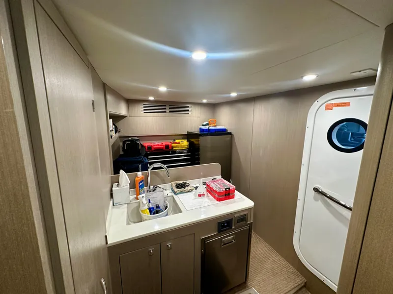 Slide: The Image of 2024 Sirena 68 yacht interior with kitchenette, sink, and storage, featuring modern design and lighting. - 49