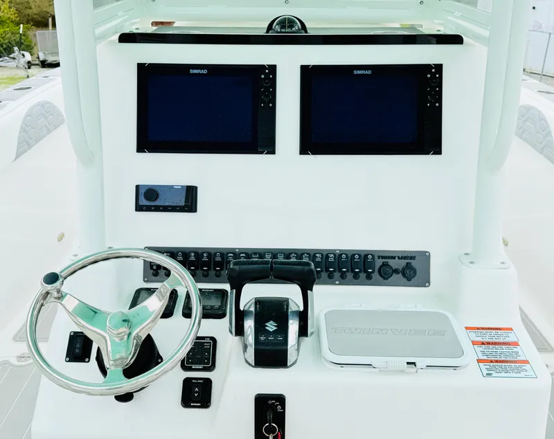 Slide: The Image of 2022 Twin Vee 280 GFX CC boat dashboard with dual Simrad displays and Suzuki controls. - 1