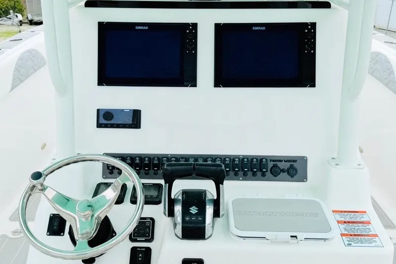 Slide: The Image of 2022 Twin Vee 280 GFX CC boat dashboard with dual Simrad displays and steering wheel. - 25