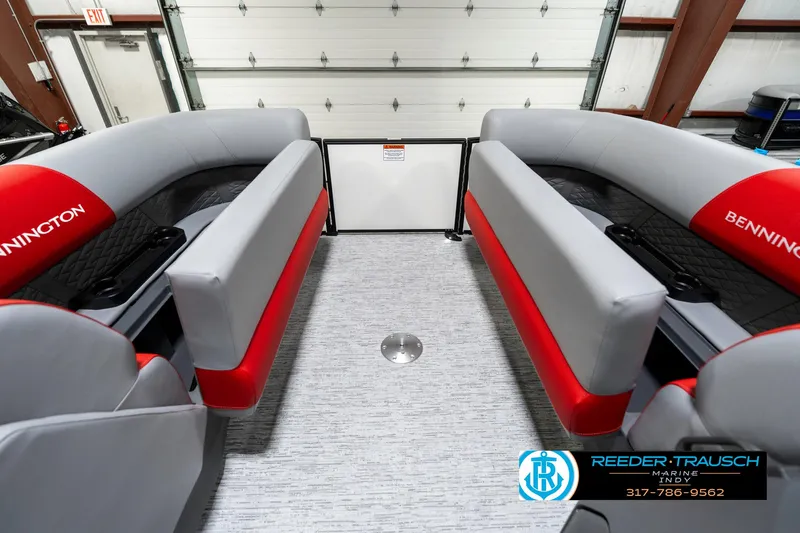 Slide: The Image of 2025 Bennington 21 SSB boat interior with gray and red seating in a garage. - 23