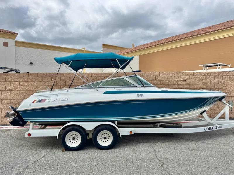 The Image of 1994 Cobalt 222 boat on trailer with blue canopy, parked outdoors. - 0