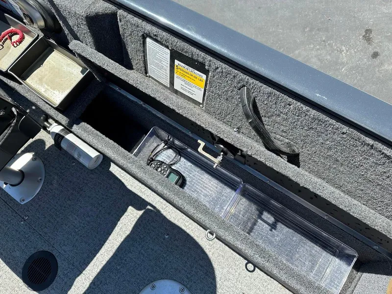 Slide: The Image of 2020 Tracker Pro Guide V-16 SC boat interior storage compartment with safety labels and accessories. - 27