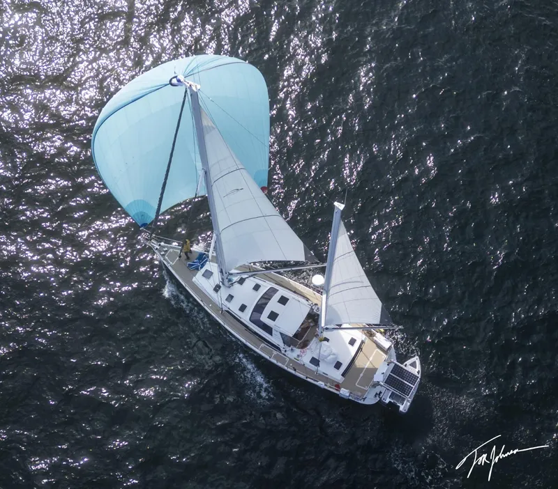 Slide: The Image of Aerial view of 2018 Amel 55 sailboat with blue spinnaker on open water. - 1