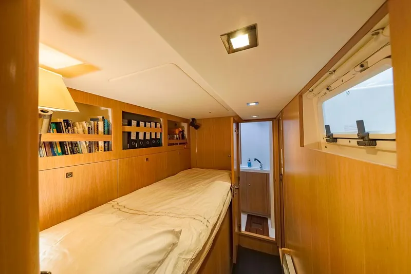 Slide: The Image of Cozy cabin interior of 2018 Amel 55 yacht with bed, bookshelf, and window. - 19
