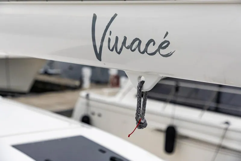 Slide: The Image of Sailboat boom with "Vivacé" text, Amel 55, 2018 model, docked at marina. - 45