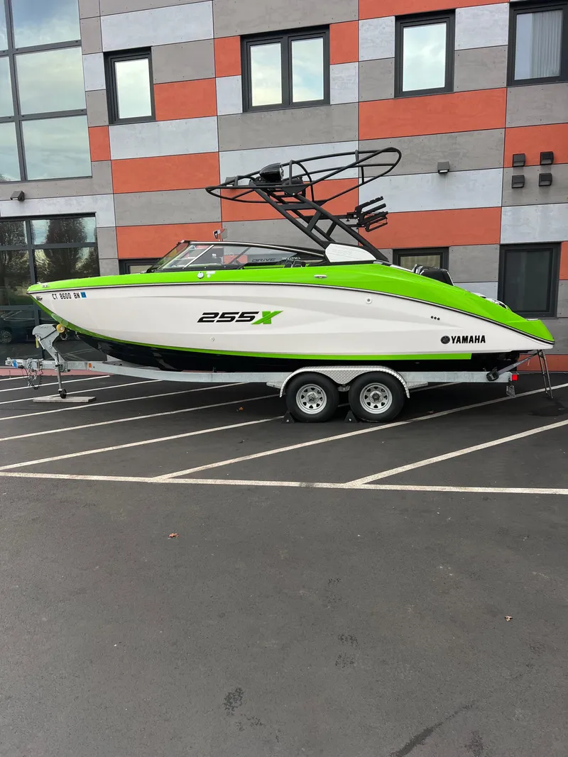 The Image of 2022 Yamaha Boats 255XD in parking lot, vibrant green and white design. - 1