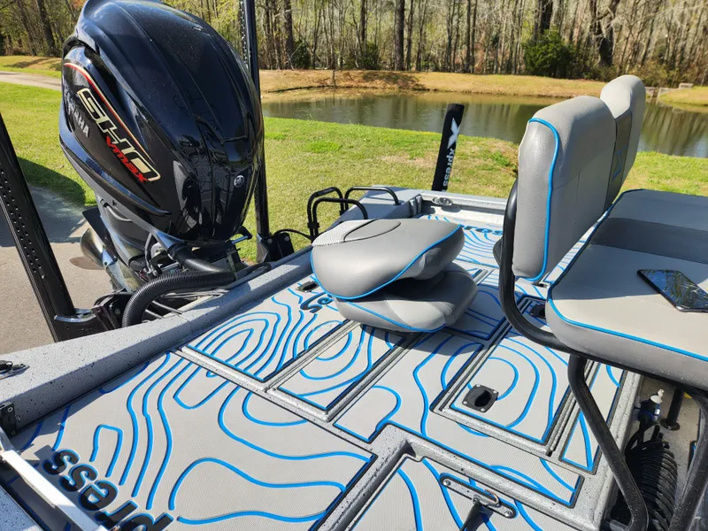 Slide: The Image of 2022 Xpress H22B boat with sleek seating and powerful engine by a serene lake. - 10