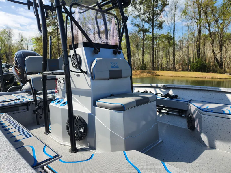 Slide: The Image of 2022 Xpress H22B boat interior with seating and console, set against a serene lake backdrop. - 11