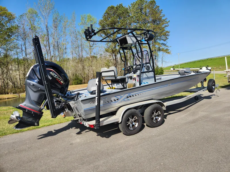 Slide: The Image of 2022 Xpress H22B boat on trailer, featuring powerful outboard motor, parked outdoors. - 2