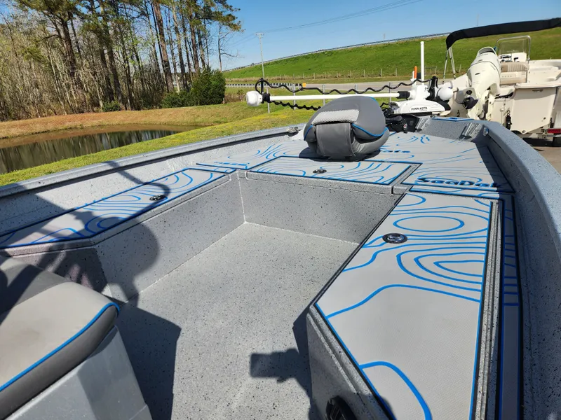 Slide: The Image of 2022 Xpress H22B boat interior with seating and storage, near a pond and trees. - 9