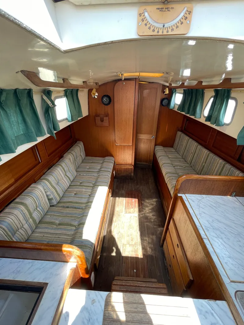 Slide: The Image of 1979 Bristol 32 yacht interior with wood finish, green curtains, and striped seating. - 19