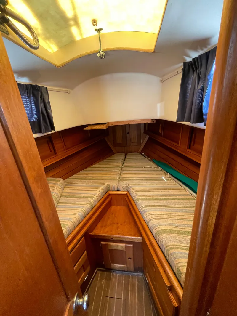 Slide: The Image of 1979 Bristol 32 sailboat cabin with wood interior and striped cushions. - 20