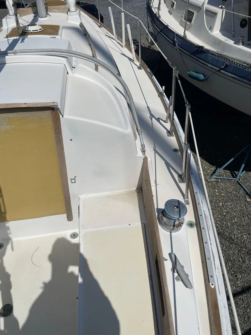 Slide: The Image of 1979 Bristol 32 sailboat deck with winch and railing, docked beside another boat. - 7