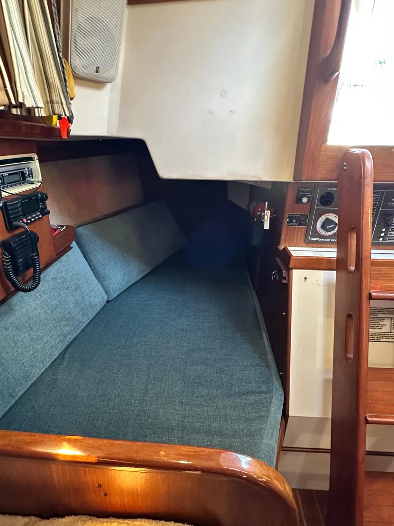 Slide: The Image of 1988 Cape Dory 30 MK II cabin interior with blue cushioned seating and navigation equipment. - 24