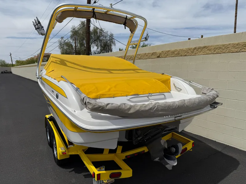 Slide: The Image of 2008 Reinell Bowrider 220LSE with yellow cover on trailer, parked near a wall. - 36