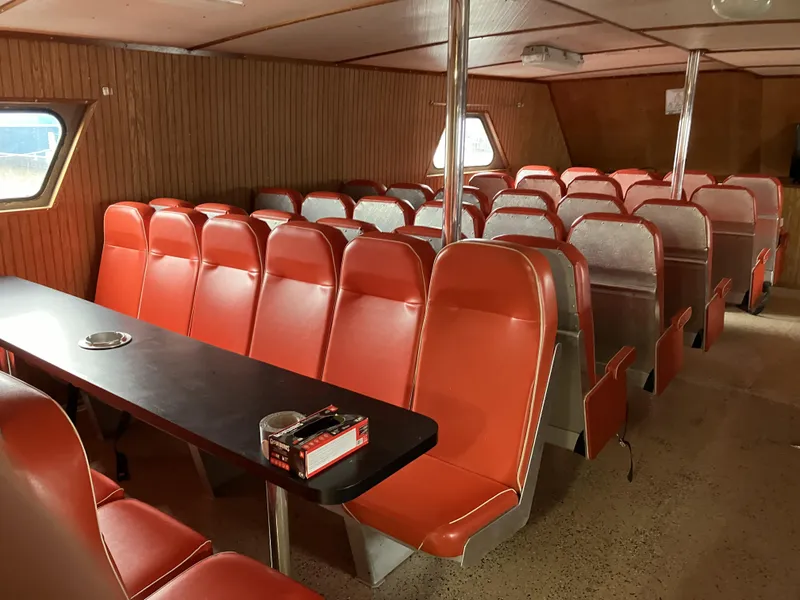 Slide: The Image of Interior of a 1994 commercial offshore crew boat with orange seating and a long table. - 10