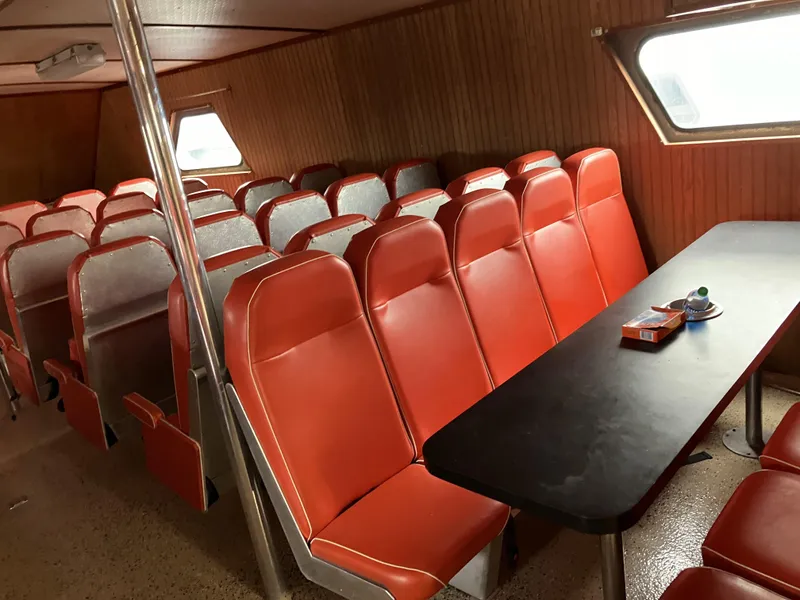 Slide: The Image of Interior of a 1994 Offshore Crew Boat with red seating and a black table. - 12