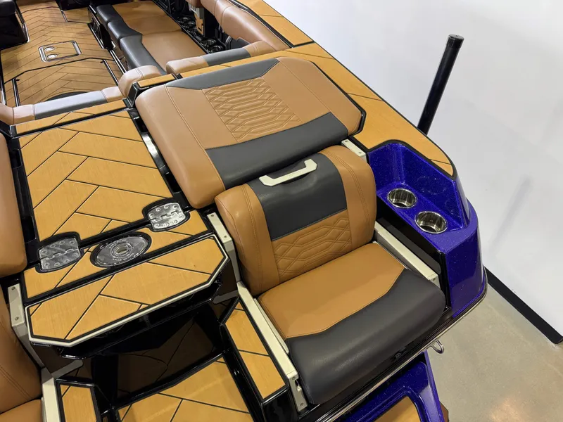 Slide: The Image of 2023 Malibu Wakesetter 26 LSV interior with tan and black seating, cup holders, and stylish flooring. - 11