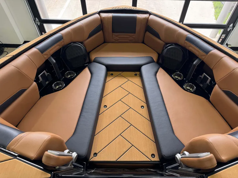 Slide: The Image of 2023 Malibu Wakesetter 26 LSV interior with tan and black seating, cup holders, and stylish flooring. - 17