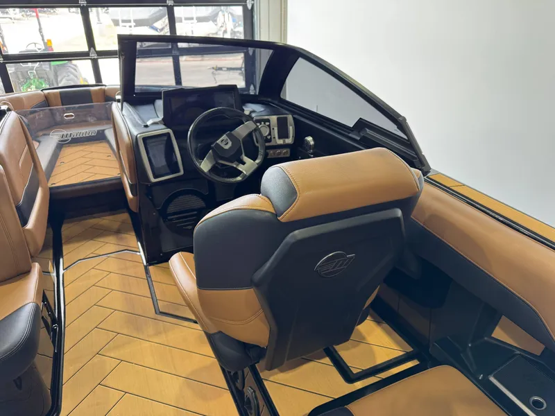 Slide: The Image of 2023 Malibu Wakesetter 26 LSV interior with tan and black seating, modern dashboard, and steering wheel. - 23