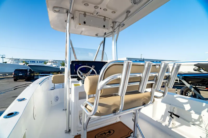 Slide: The Image of 2018 Sea Hunt Triton 210 boat interior with helm and seating, docked under clear blue sky. - 12
