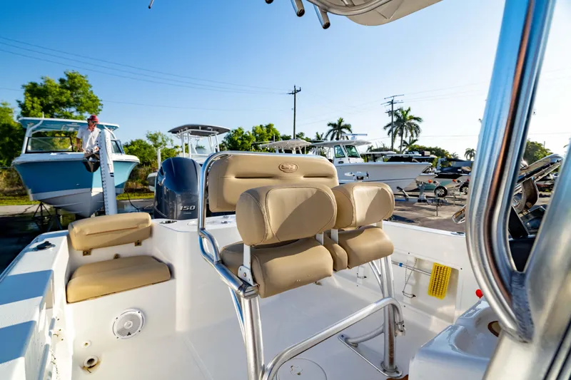 Slide: The Image of 2018 Sea Hunt Triton 210 boat interior with beige seating, parked in a sunny marina. - 20