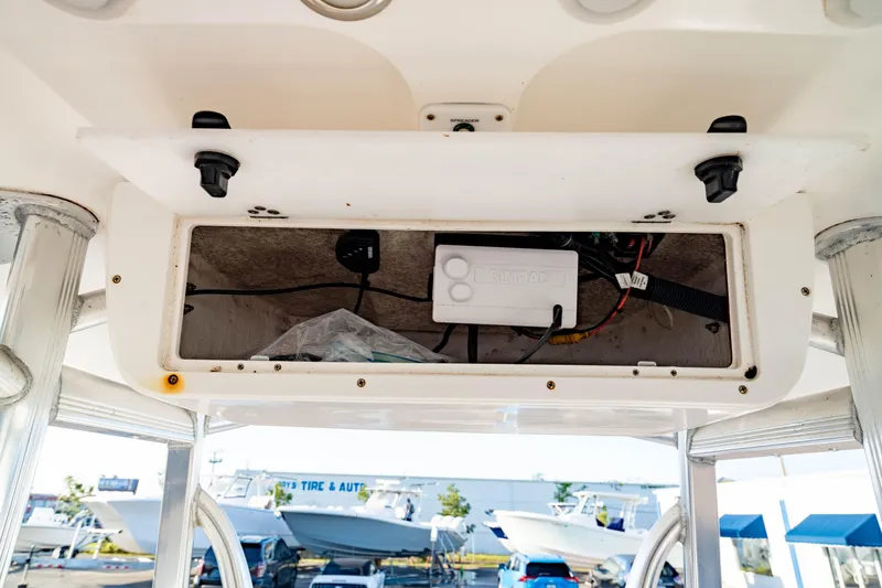 Slide: The Image of 2018 Sea Hunt Triton 210 boat console storage compartment with wiring and equipment. - 23