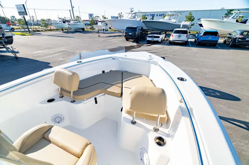 Slide: The Image of 2018 Sea Hunt Triton 210 boat interior with beige seating, parked in a lot with other vehicles. - 33