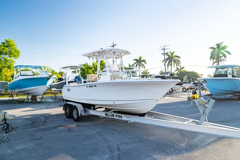 Slide: The Image of 2018 Sea Hunt Triton 210 boat on trailer, parked outdoors with palm trees in background. - 36