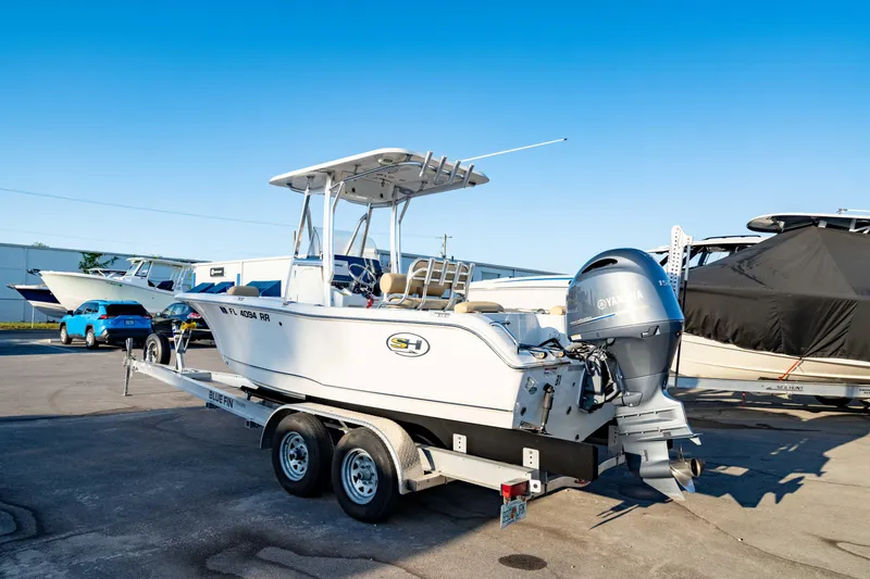 Slide: The Image of 2018 Sea Hunt Triton 210 boat on trailer, parked outdoors under clear blue sky. - 7