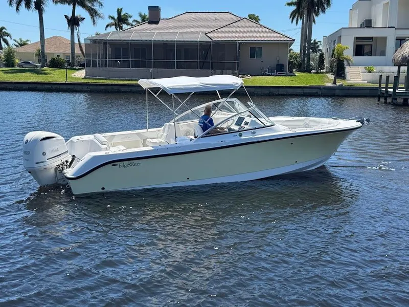 Slide: The Image of 2009 Edgewater 245 CX boat cruising on a sunny waterfront with palm trees. - 13