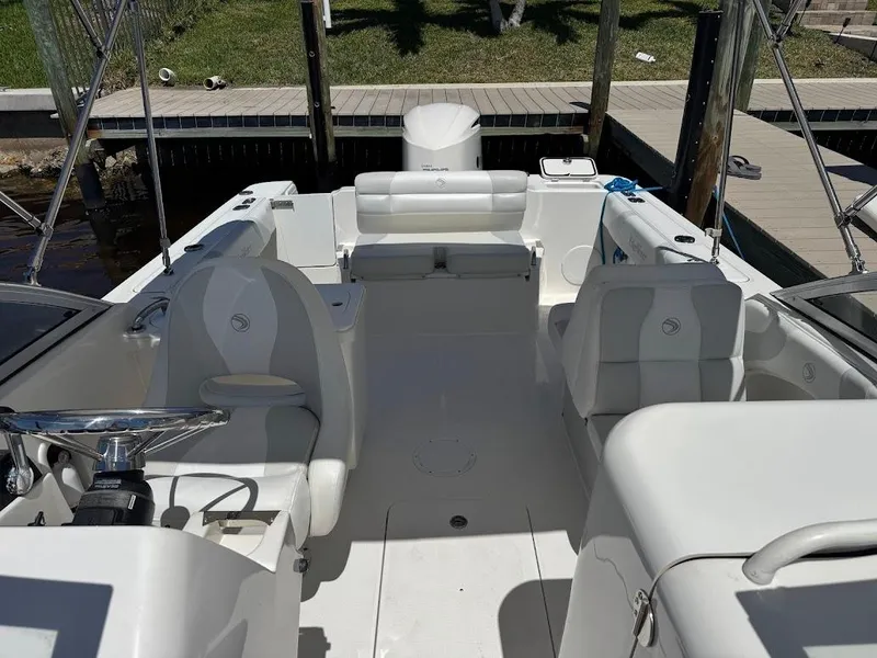 Slide: The Image of 2009 Edgewater 245 CX boat interior with white seating and steering wheel, docked by the water. - 18