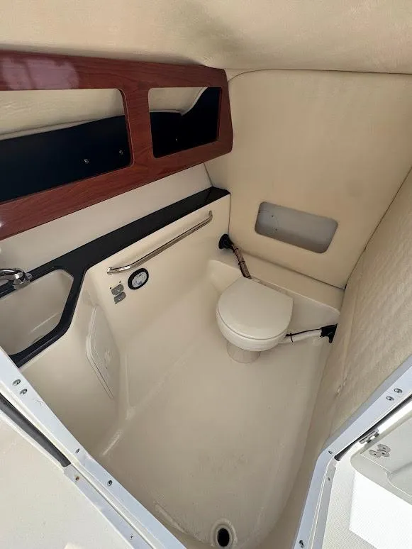 Slide: The Image of 2009 Edgewater 245 CX boat interior with compact marine toilet and wooden accents. - 21