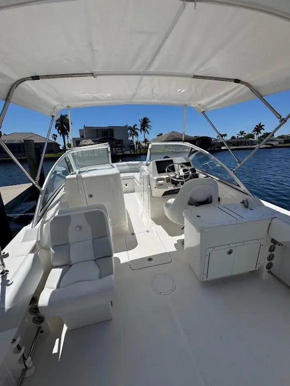 Slide: The Image of 2009 Edgewater 245 CX boat interior with seating, helm, and canopy on a sunny day. - 35