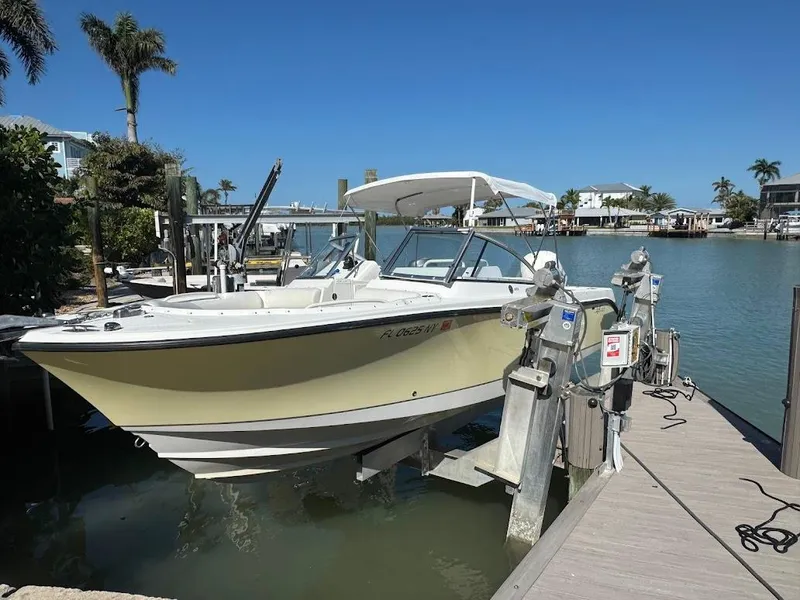 Slide: The Image of 2009 Edgewater 245 CX boat docked by waterfront, sunny day, palm trees in background. - 38
